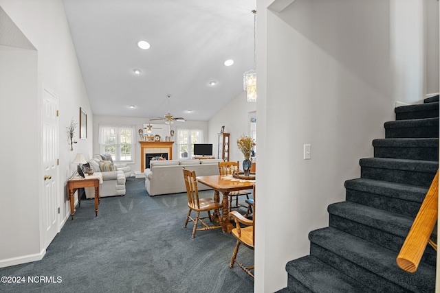 staircase featuring ceiling fan, a fireplace, carpet floors, and vaulted ceiling