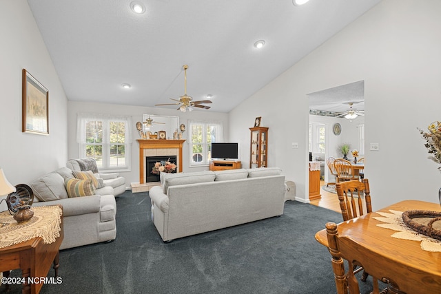 living room with dark colored carpet, a healthy amount of sunlight, lofted ceiling, and a tiled fireplace