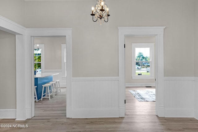 hall featuring an inviting chandelier and light hardwood / wood-style floors