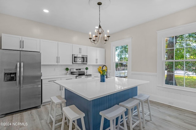 kitchen featuring appliances with stainless steel finishes, a wealth of natural light, and white cabinets