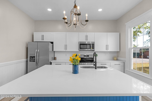 kitchen featuring white cabinetry, stainless steel appliances, sink, and a kitchen island with sink