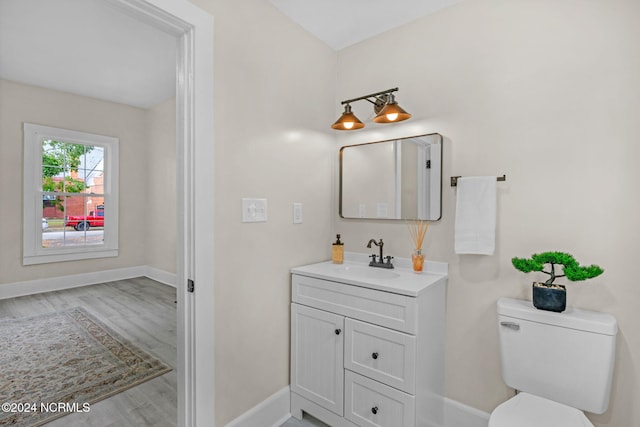 bathroom with toilet, vanity, and wood-type flooring