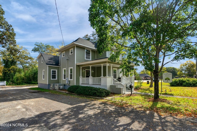 view of front of home with central AC, a porch, and a front lawn