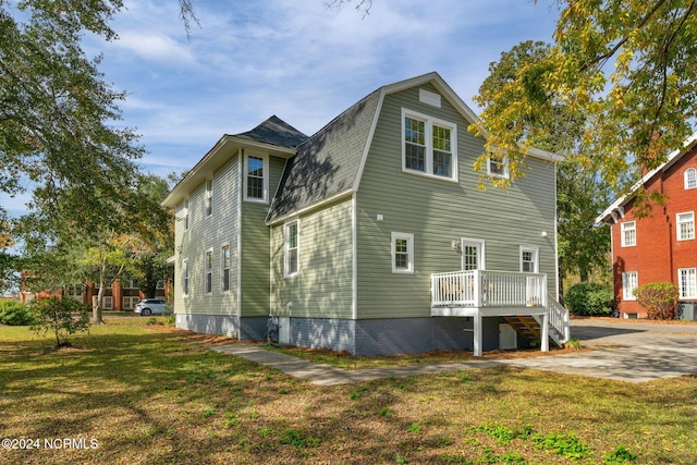 back of house featuring a wooden deck and a yard
