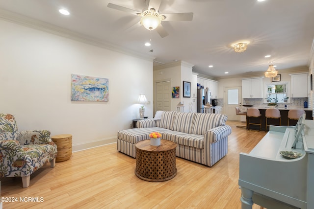 living room with light hardwood / wood-style floors, ornamental molding, and ceiling fan