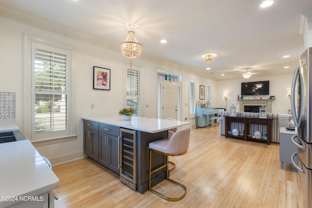 kitchen featuring kitchen peninsula, wine cooler, hanging light fixtures, a breakfast bar, and light hardwood / wood-style floors