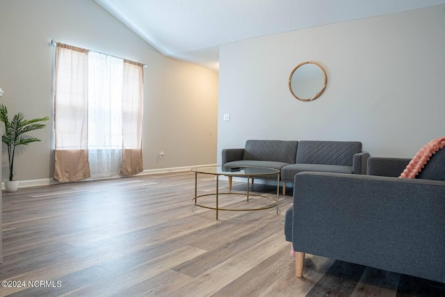 living room featuring lofted ceiling, baseboards, and wood finished floors