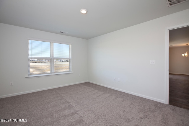 empty room featuring carpet and a notable chandelier