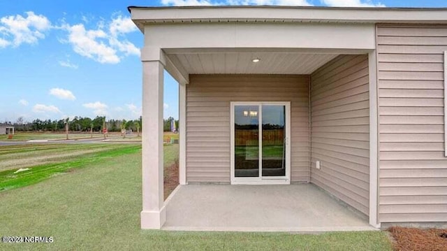 property entrance featuring a lawn and a patio