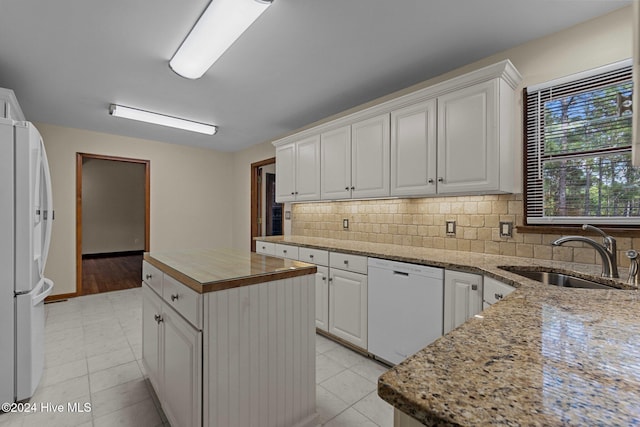 kitchen featuring a center island, white appliances, sink, and white cabinetry