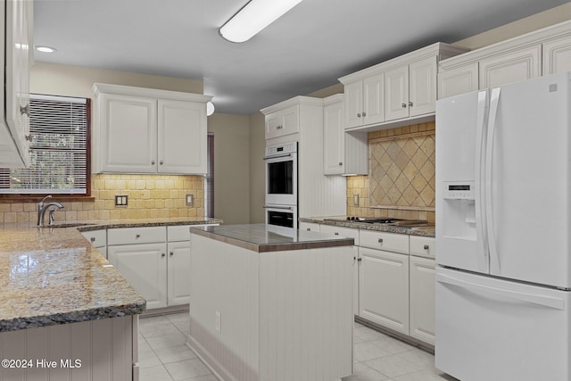 kitchen featuring white cabinets, white appliances, a kitchen island, and sink