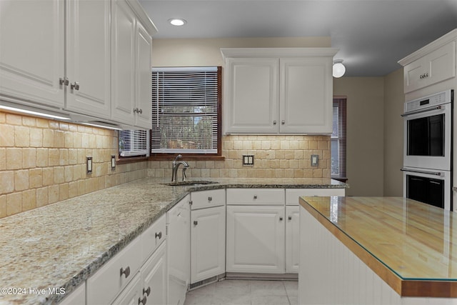 kitchen with white appliances, backsplash, white cabinetry, and sink