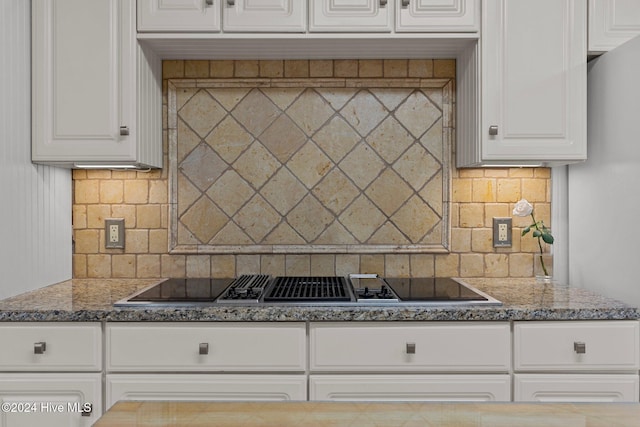 kitchen with dark stone countertops, decorative backsplash, stovetop, and white cabinets