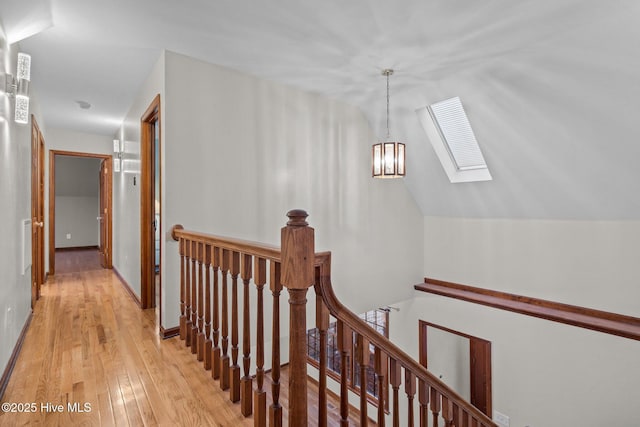 corridor featuring light hardwood / wood-style floors and lofted ceiling with skylight