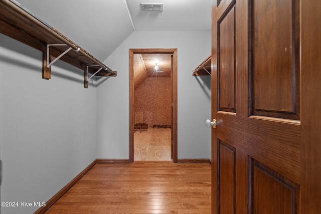 walk in closet with light hardwood / wood-style floors and vaulted ceiling