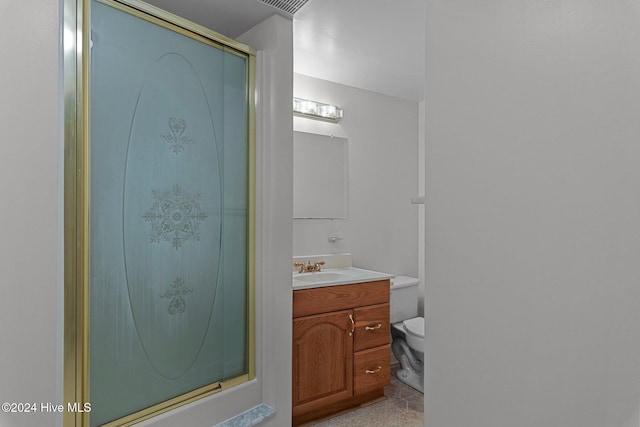 bathroom featuring vanity, toilet, and a shower with shower door