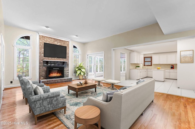 living room featuring light hardwood / wood-style flooring and a brick fireplace