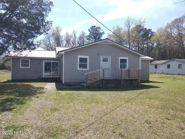 rear view of property featuring a deck and a lawn