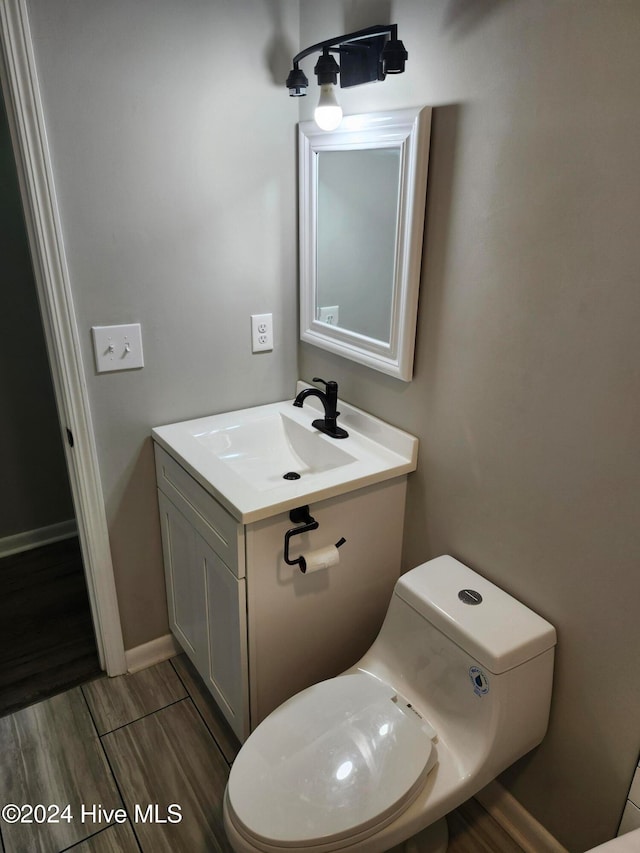 bathroom featuring toilet, vanity, and wood-type flooring