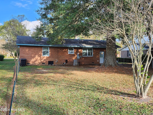 rear view of property featuring central air condition unit and a yard