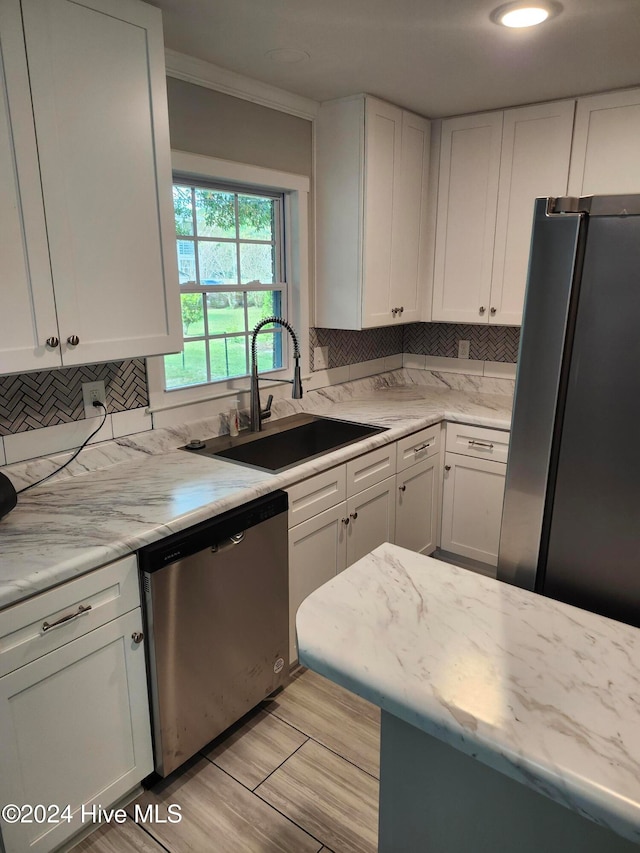 kitchen featuring appliances with stainless steel finishes, white cabinetry, tasteful backsplash, and sink