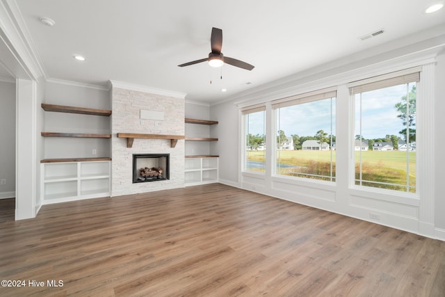 unfurnished living room with a stone fireplace, hardwood / wood-style floors, and ornamental molding