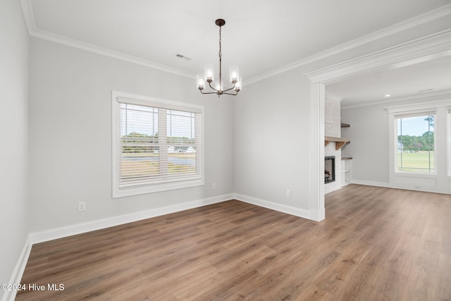 interior space with an inviting chandelier, a wealth of natural light, hardwood / wood-style floors, and crown molding