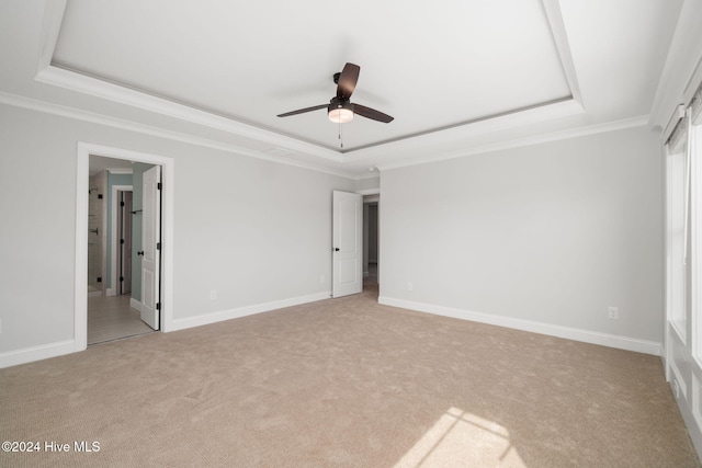 unfurnished bedroom with light colored carpet, ceiling fan, and a tray ceiling