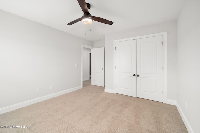 unfurnished bedroom featuring a closet, light colored carpet, and ceiling fan