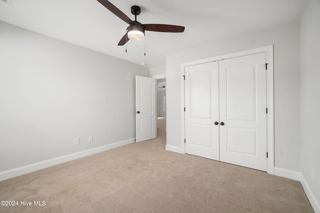 unfurnished bedroom with ceiling fan, a closet, and light colored carpet