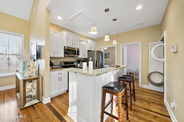 kitchen with white cabinetry, light hardwood / wood-style floors, stainless steel appliances, and pendant lighting