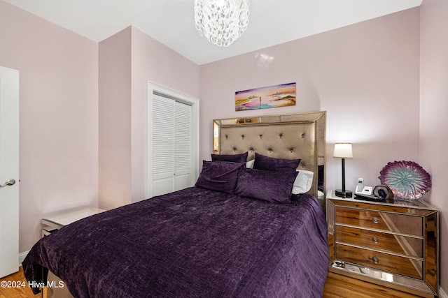 bedroom with a closet, a notable chandelier, and hardwood / wood-style floors