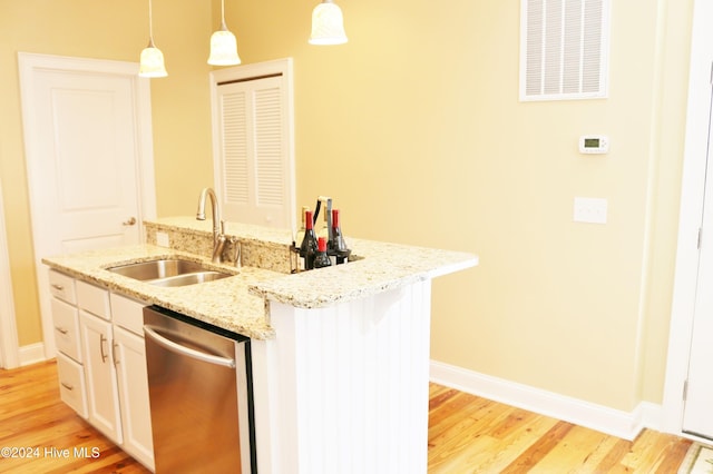 kitchen featuring sink, dishwasher, a kitchen island with sink, and light wood-type flooring