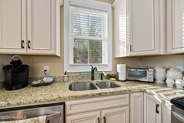 kitchen featuring white cabinets, light stone counters, sink, and beverage cooler