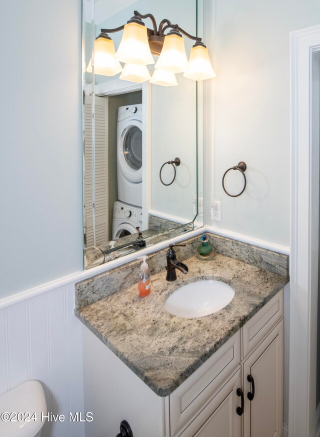 bathroom featuring vanity, toilet, and stacked washing maching and dryer