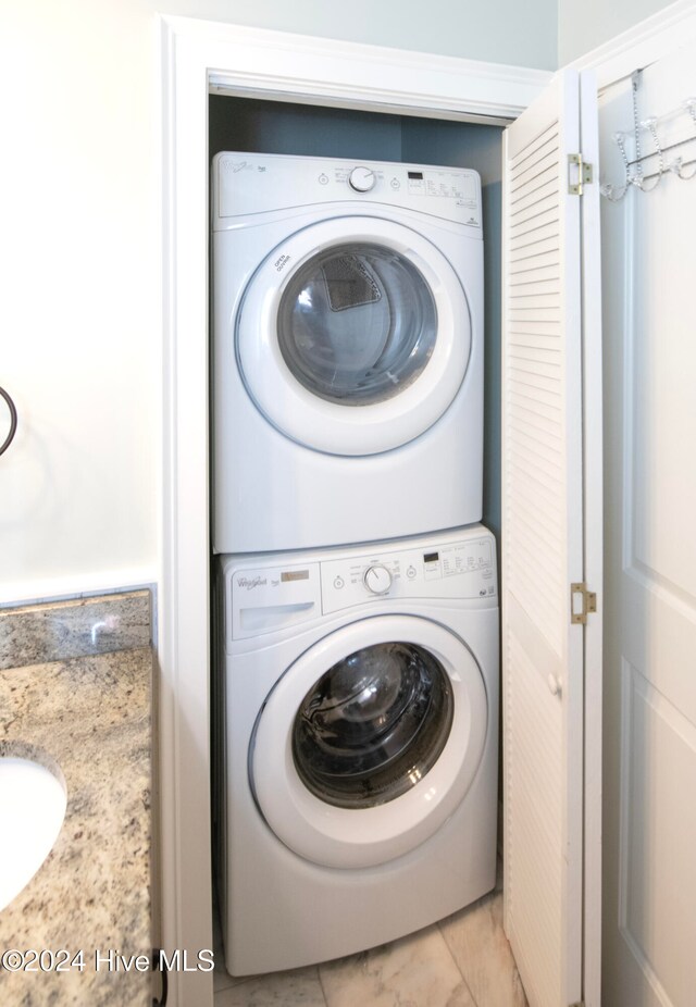 washroom featuring light tile patterned floors and stacked washing maching and dryer