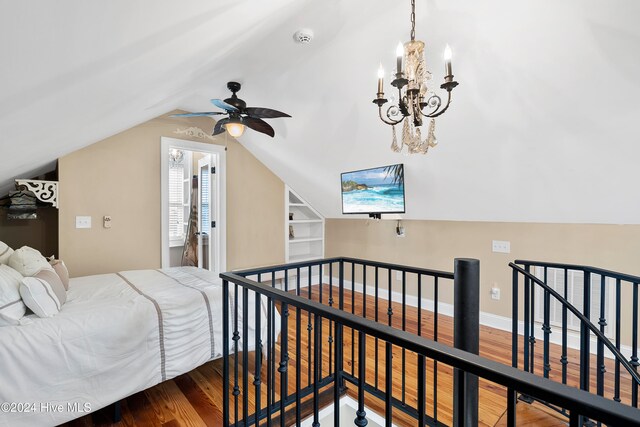 bedroom featuring wood-type flooring, lofted ceiling, and ceiling fan with notable chandelier