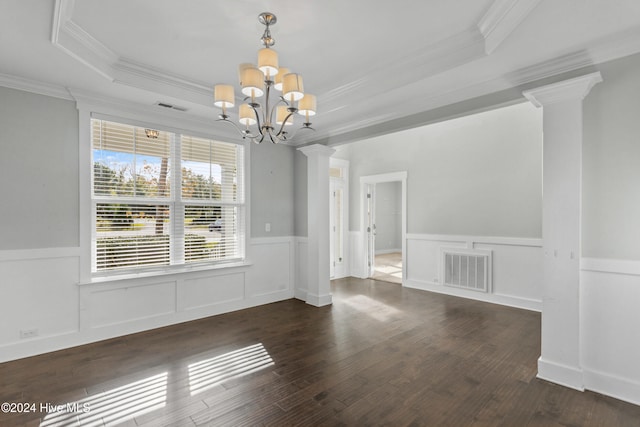 unfurnished dining area featuring a tray ceiling, dark hardwood / wood-style flooring, crown molding, an inviting chandelier, and decorative columns