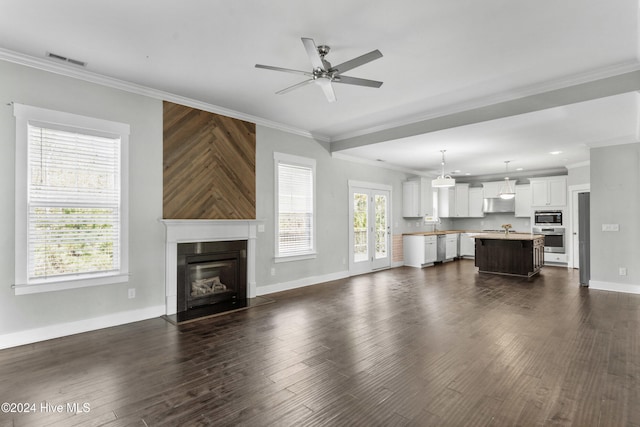 unfurnished living room featuring crown molding, a wealth of natural light, and dark wood-type flooring