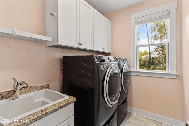 clothes washing area with cabinets, light tile patterned floors, separate washer and dryer, and sink