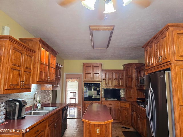 kitchen with black appliances, sink, a textured ceiling, a center island, and decorative backsplash