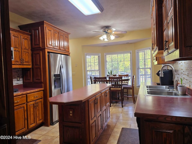 kitchen with tasteful backsplash, sink, a kitchen island, ceiling fan, and stainless steel fridge with ice dispenser