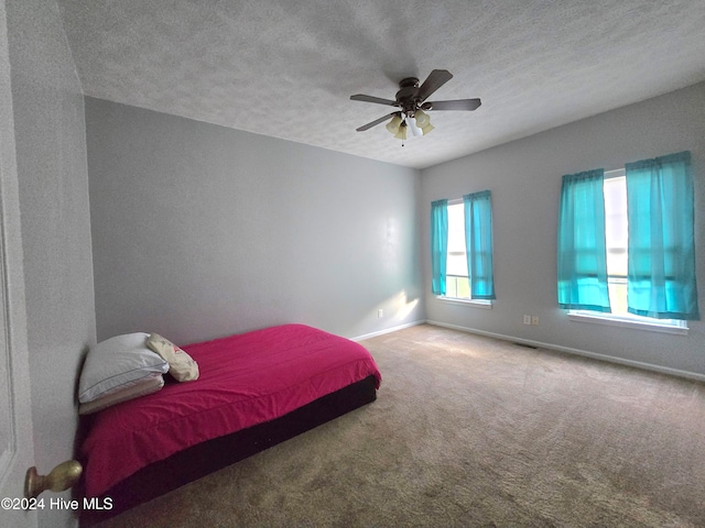 carpeted bedroom featuring a textured ceiling and ceiling fan