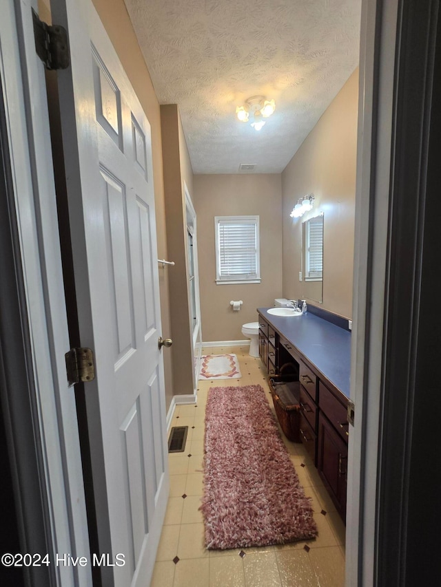 bathroom featuring vanity, toilet, a textured ceiling, and tile patterned flooring