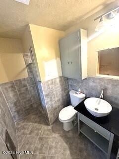 bathroom with vanity, tile walls, a textured ceiling, and toilet