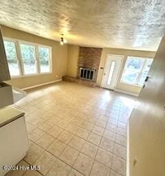 unfurnished living room featuring a brick fireplace, light tile patterned floors, and plenty of natural light