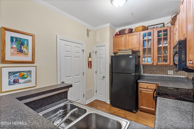 kitchen with crown molding, hardwood / wood-style floors, black appliances, and decorative backsplash