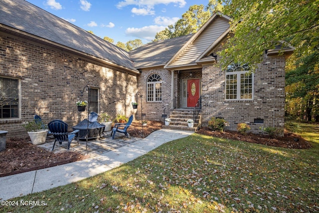 entrance to property with a yard, brick siding, crawl space, and a patio area