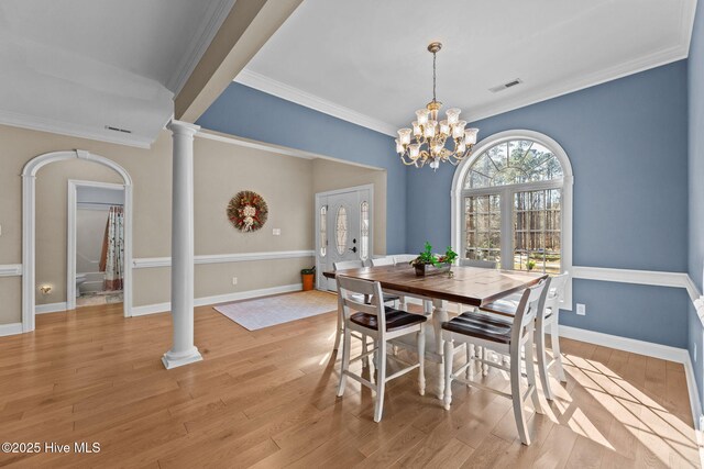 dining area featuring visible vents, baseboards, light wood-style flooring, crown molding, and ornate columns