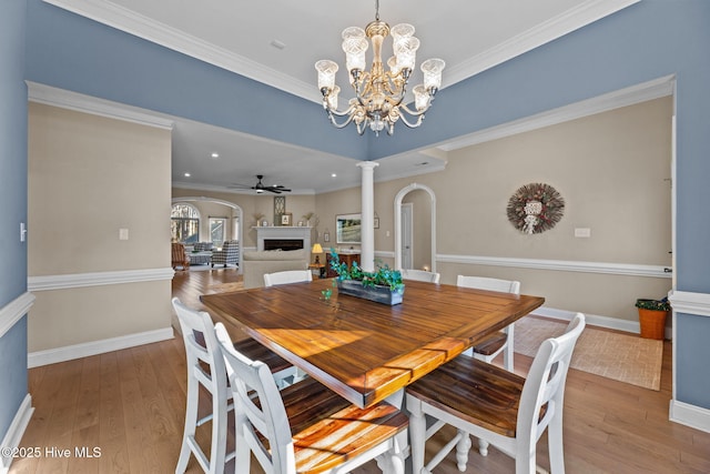 dining space with decorative columns, crown molding, ceiling fan with notable chandelier, and hardwood / wood-style flooring